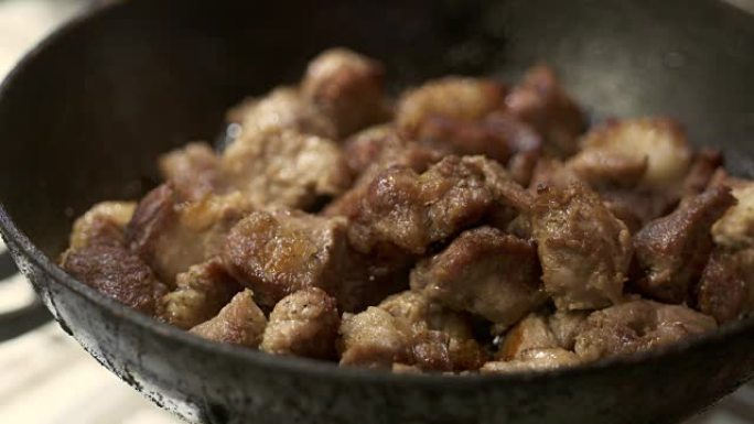 吃脆皮炸猪肉。在加热的铁锅特写中油炸肉块