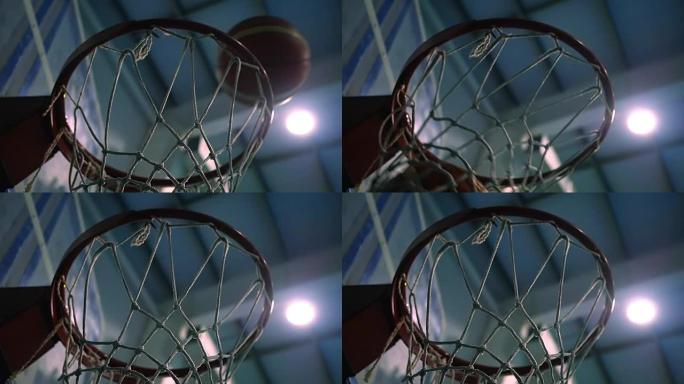 在探照灯的背景下将球扔进篮球圈。慢动作