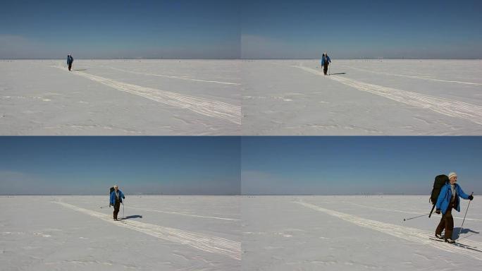 穿着蓝色夹克和背包的男人正在冰冻的河流的冰上滑雪