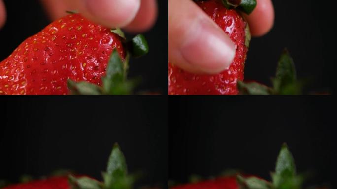 男人在黑暗的背景上拿一个草莓，特写