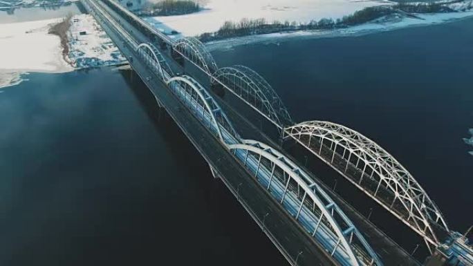 汽车和火车在冰冻的河流空中无人机镜头上的桥上移动