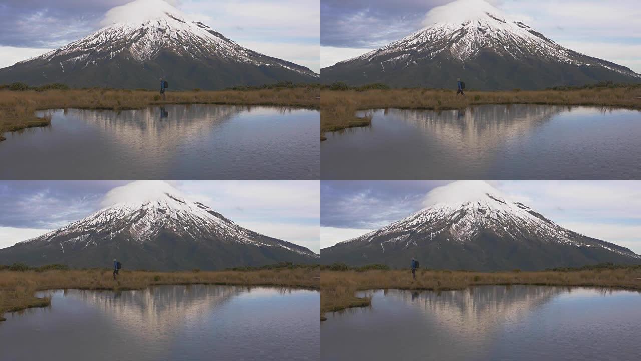 慢动作-旅行者穿越新西兰北岛的塔拉纳基火山，并在湖中反射tho山和登山者。新泽兰