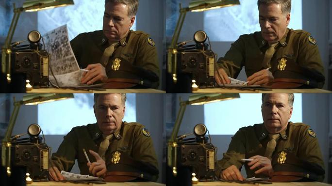 第二次世界大战的陆军航空兵上尉坐在他的办公桌旁看侦察照片