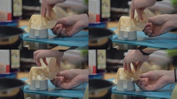 用瓷杯从烤纸上去除融化的奶酪