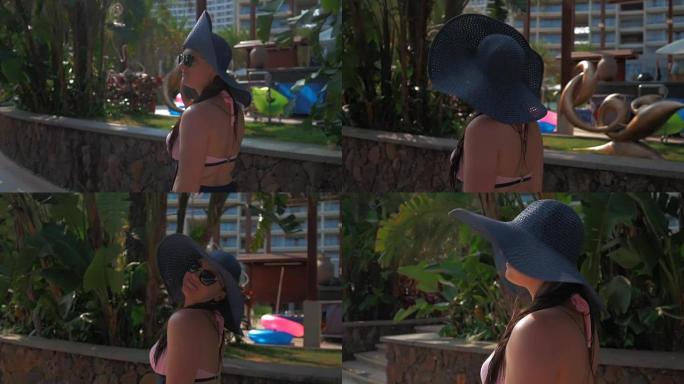 一个戴着蓝色帽子的漂亮女孩去热带城市。夏日的阳光。慢动作