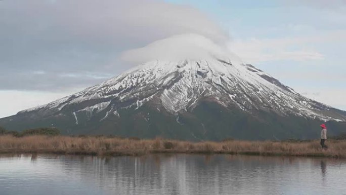 旅行者向新西兰北岛的塔拉纳基火山望去，并映入湖中的tho山和登山者的视线。新泽兰