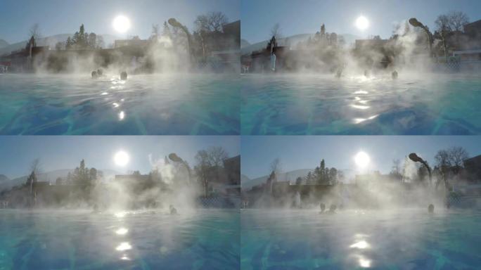 冬季，人们在温泉浴池的天然热水中，雪和水蒸汽蒸发被阳光照射