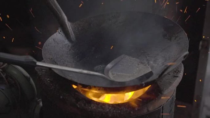 热锅里有油，炉子里燃烧的煤混合在一起，形成炽热的灰尘。慢动作。