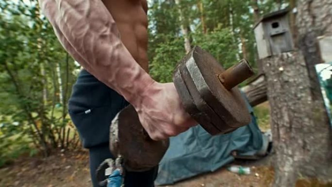 重铁手工哑铃在森林中肌肉发达的人的手中锻炼