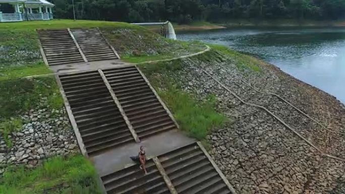 空中: 一个女孩从湖边的楼梯上走下来。