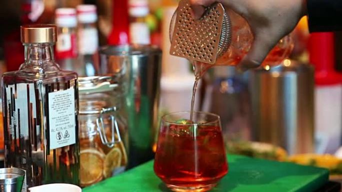 调酒师在酒吧将鸡尾酒与酒杯混合，将酒保手倒入酒杯中