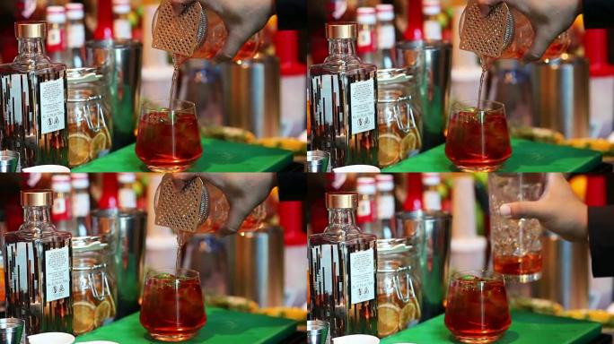 调酒师在酒吧将鸡尾酒与酒杯混合，将酒保手倒入酒杯中
