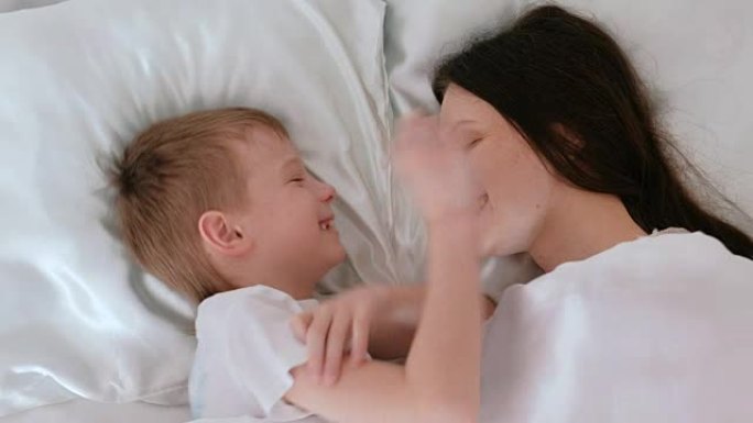 妈妈和儿子醒来。妈妈亲吻并拥抱她的儿子。