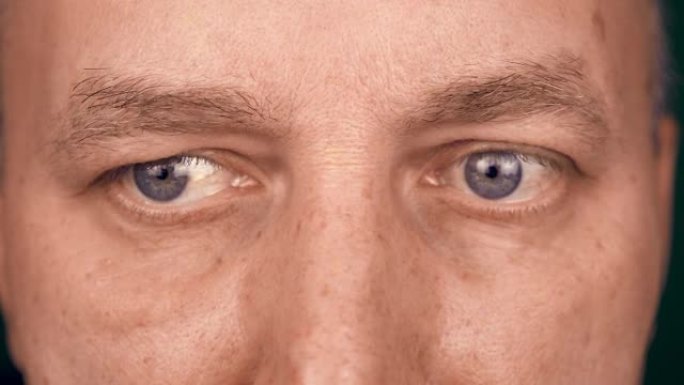 成年白人男子的极端近距离眼睛。男人读一些书电脑或信息。男性的瞳孔正在移动人脸的前视图。男人看着镜头。
