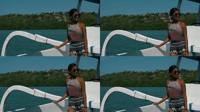 年轻漂亮的女人站在渔船上，看着风景