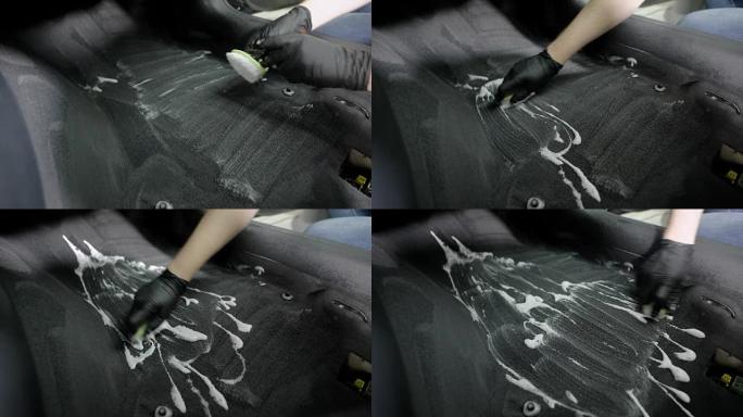 工人正在清洁汽车上的地毯，用刷子摩擦泡沫，用手拿着黑色橡胶手套，特写镜头