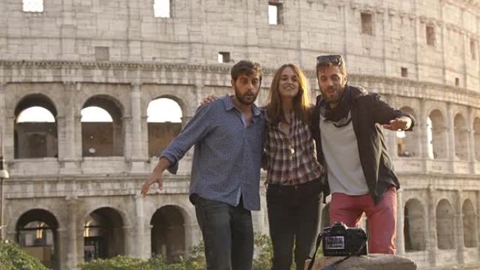 三个年轻朋友游客日落时在罗马斗兽场前跳跃自拍照片与dslr相机定时器快乐美丽的女孩长发慢动作