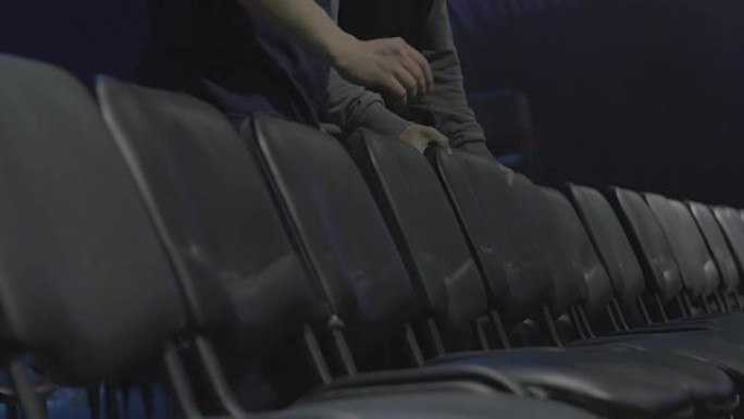剧院或电影院的椅子。男人在剧院里拉直椅子，为演讲做准备