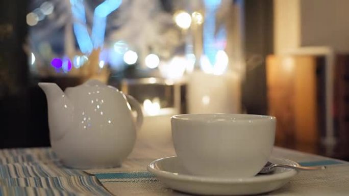城市咖啡馆的桌子上的白色茶壶和杯子。