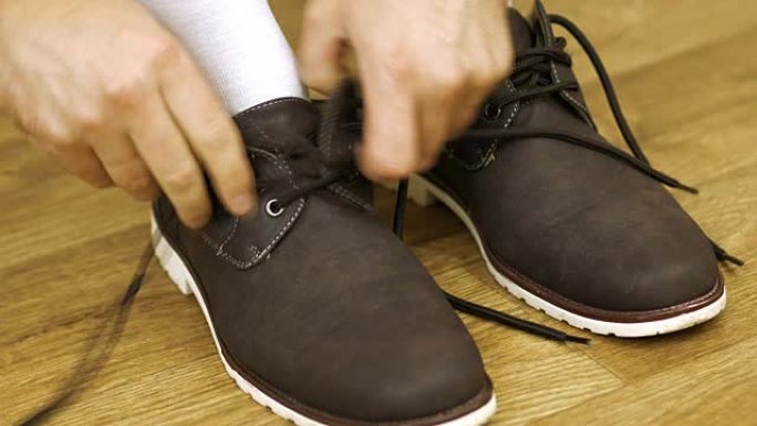 一个穿着白袜子的男人解开鞋带脱下鞋子。解开靴子。
