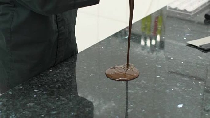 糖果的特写镜头将巧克力块倒在大理石桌上进行回火