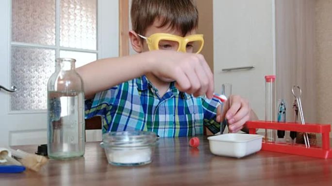在家进行化学实验。男孩用刮刀将粉末倒入小瓶中。