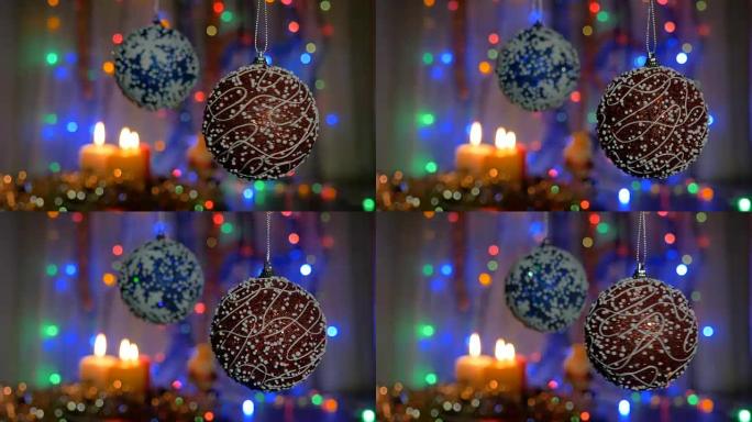 一个美丽的红球在前景旋转。模糊背景上的蓝色球。新年装饰。燃烧蜡烛。闪光花环。