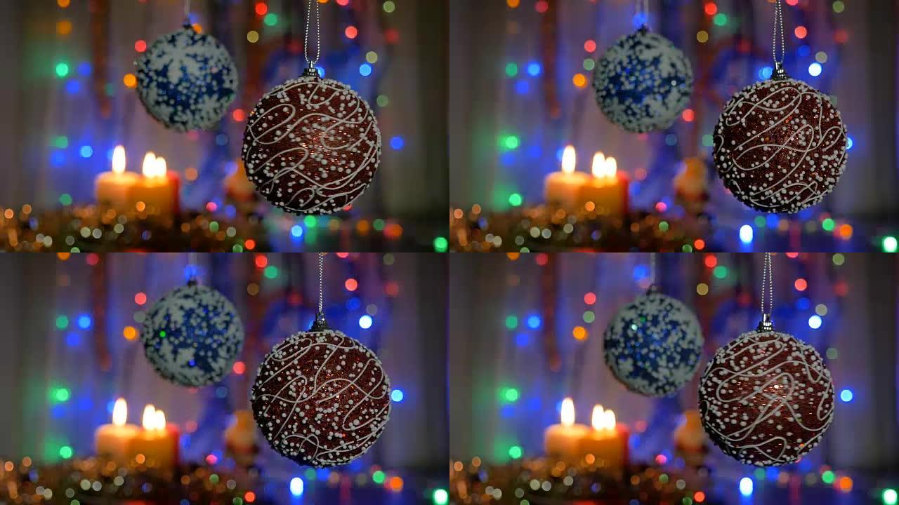 一个美丽的红球在前景旋转。模糊背景上的蓝色球。新年装饰。燃烧蜡烛。闪光花环。