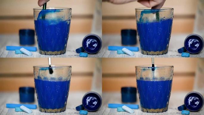 在一杯透明的水中加入一滴蓝色油漆并搅拌。水被弄脏了