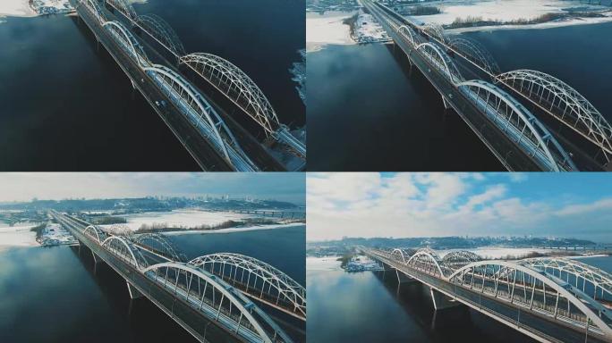 汽车和火车在冰冻的河流空中无人机镜头上的桥上移动
