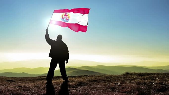 成功的剪影男子冠军挥舞着法国波利尼西亚国旗在山顶。Cinemagraph循环背景