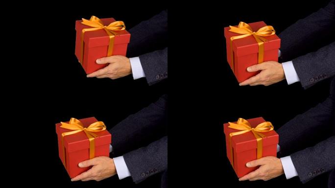 两只男性手握着带有金蝴蝶结的红色礼盒。庆祝前夕礼物盒。穿着古典西装的高加索人。阿尔法通道色度键透明背