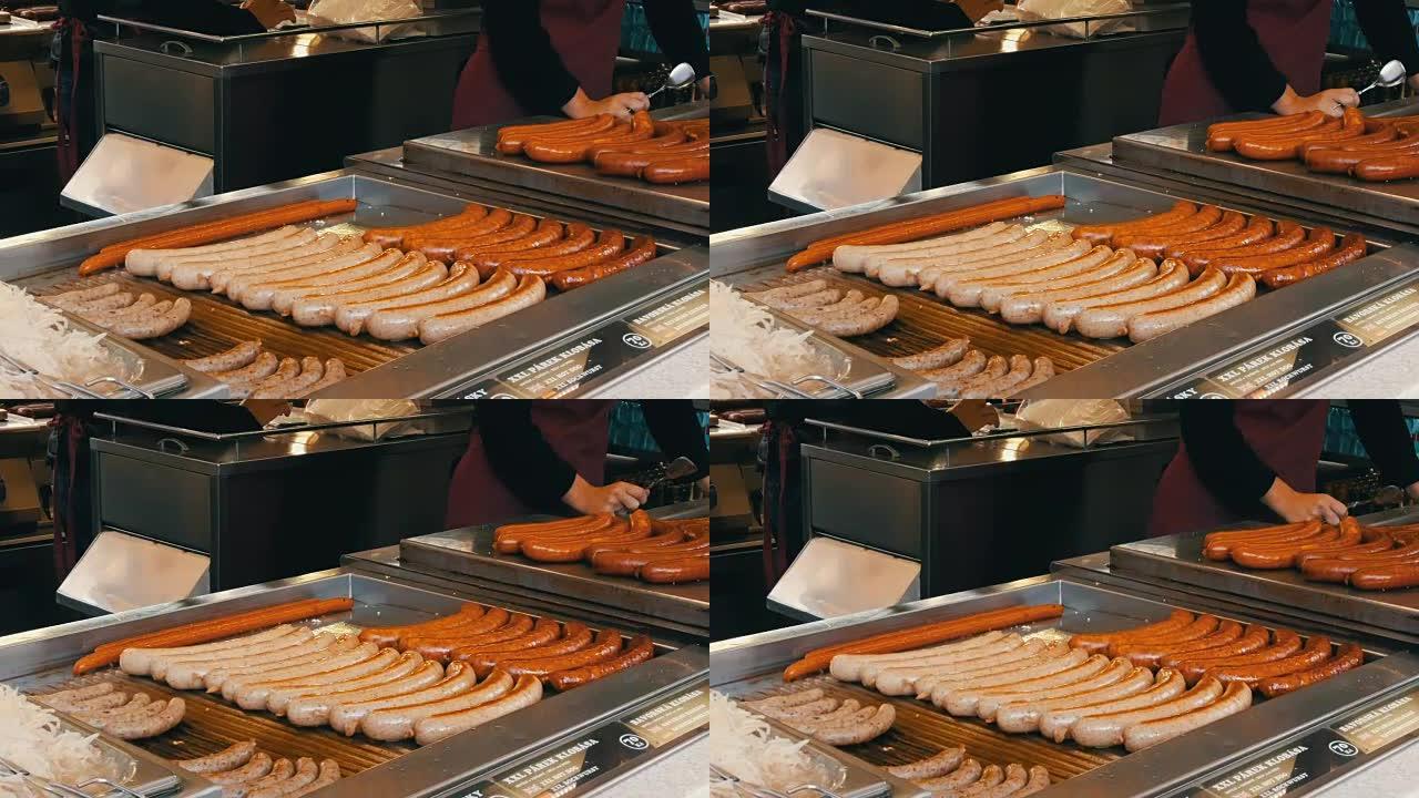 一个女推销员在烤架上烤香肠，布拉格市中心的街头食品，街道托盘柜台上的各种不同香肠