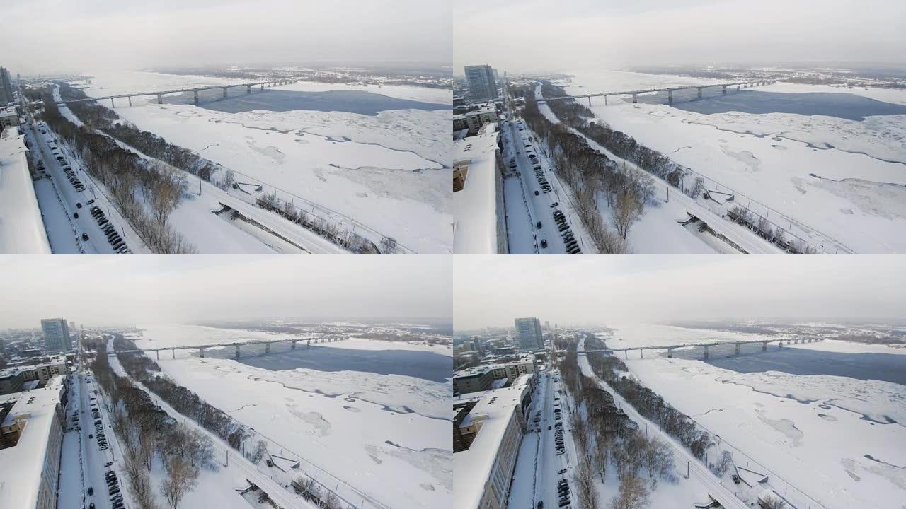 在美丽的城市或城镇下雪的冬天。夹。结冰的河流的俯视图，道路上的许多汽车，古老的建筑。大城市迷人的冬季