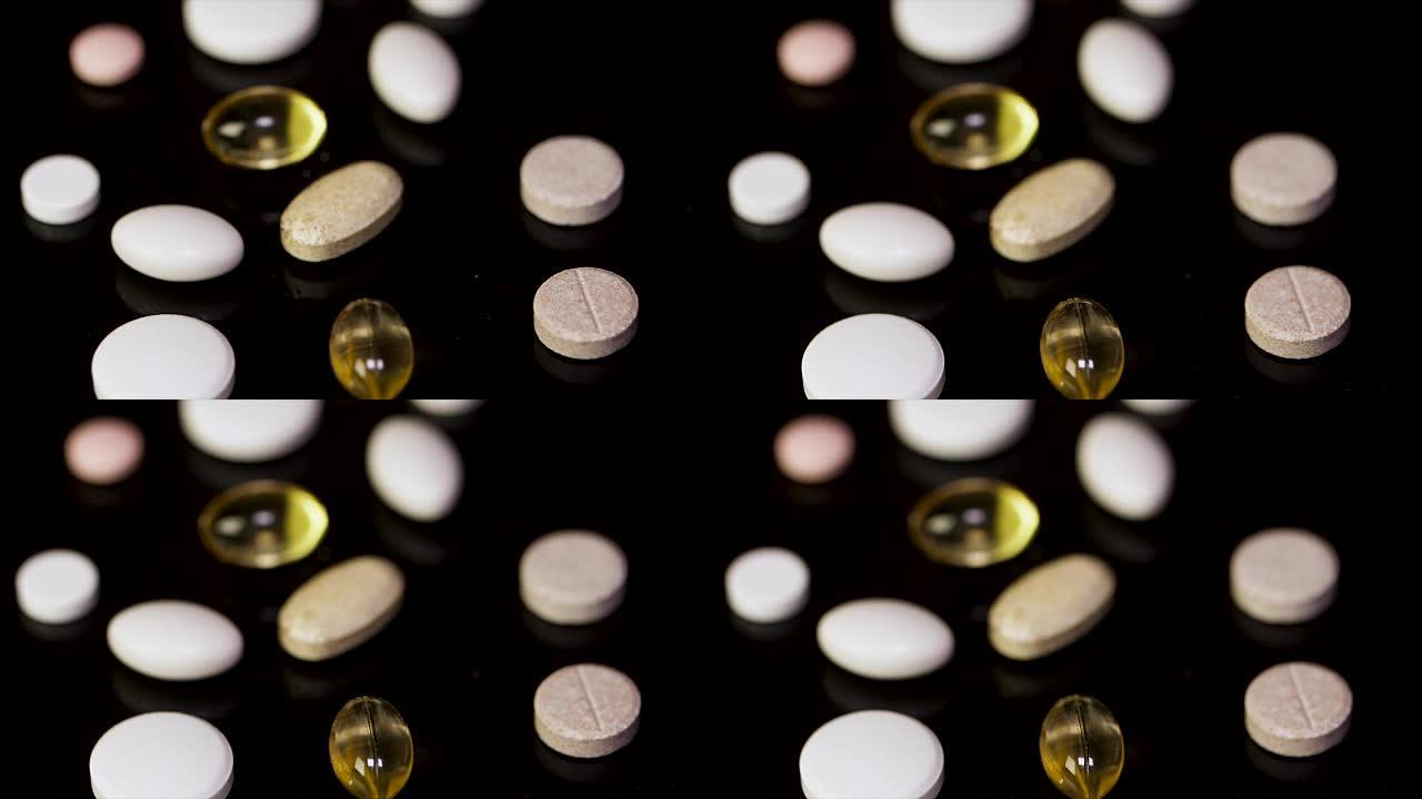 药丸。黑色背景上分散的药片。欧米茄，鱼油。平板电脑散落在黑色背景上。黑色背景上的白色和黄色药片。与药