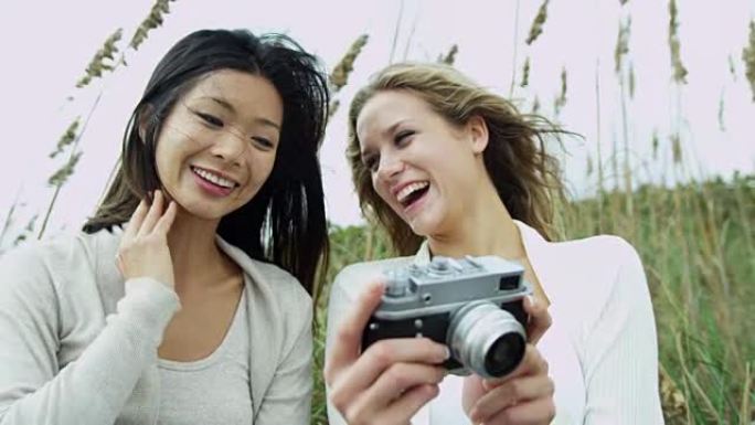 美丽的多民族女友在户外使用复古相机