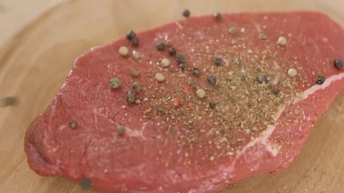 慢动作在生红肉上撒上盐和胡椒粉