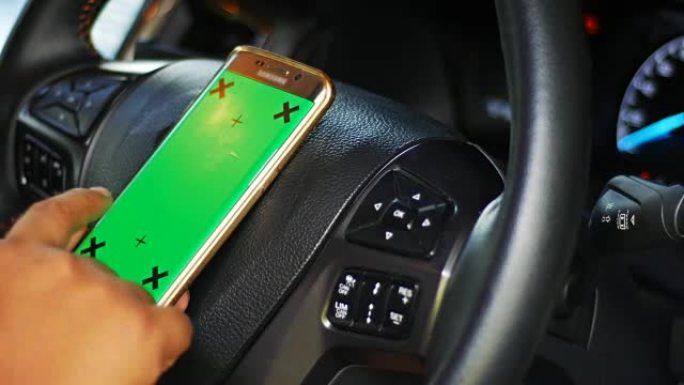 驾驶员在汽车中使用带有绿屏的智能手机，色键，多莉射击