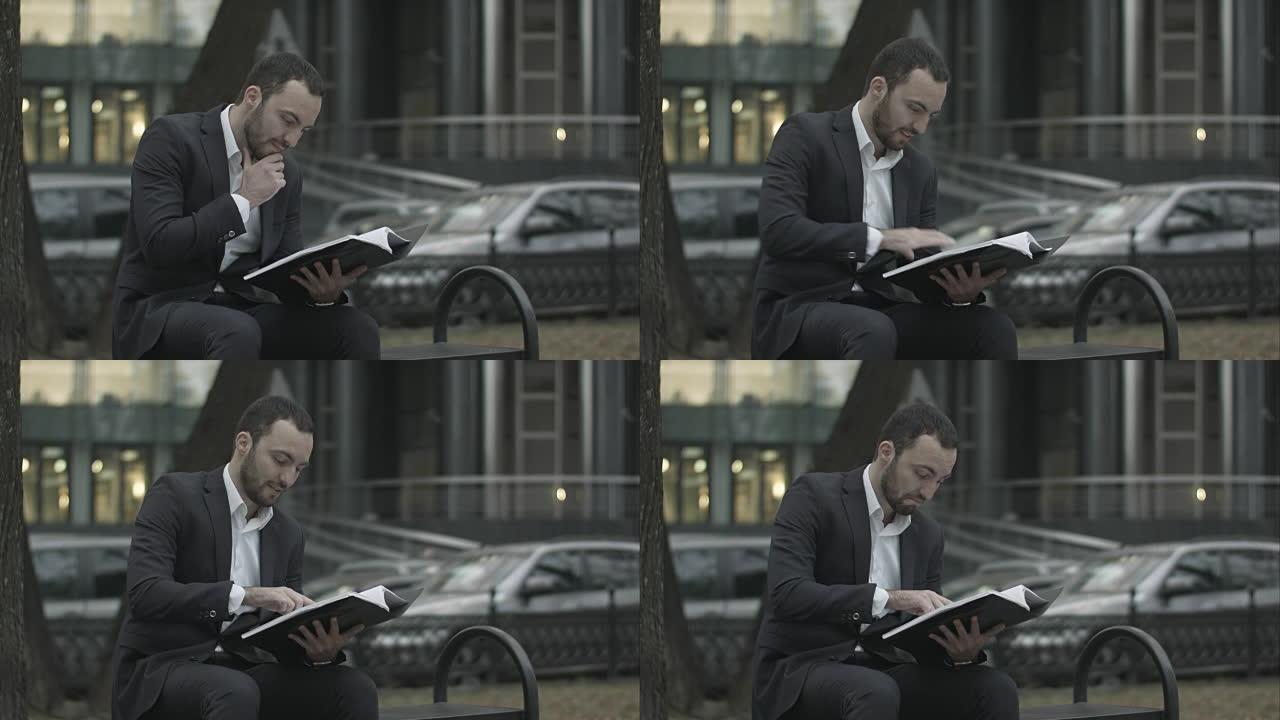西装革履的男人正兴致勃勃地读着商业计划书，坐在公园的长椅上