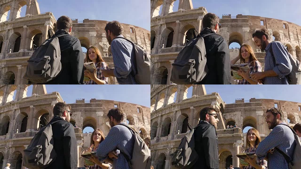 三个年轻的朋友游客站在罗马斗兽场前阅读地图指南指向背包太阳镜快乐美丽的女孩长发慢动作