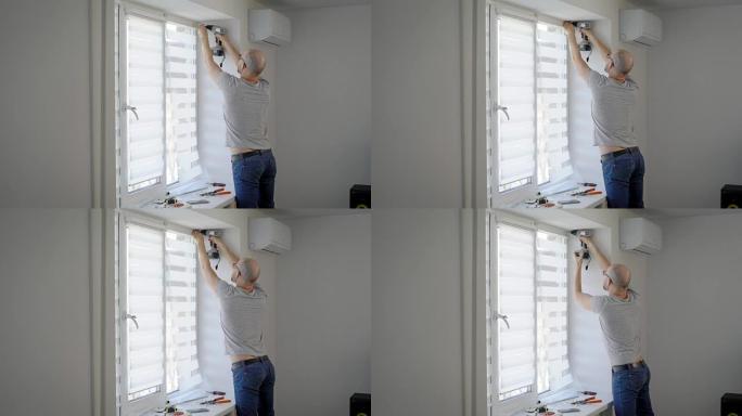 一个小时的员工在新建的公寓中进行小修，他挂在百叶窗上