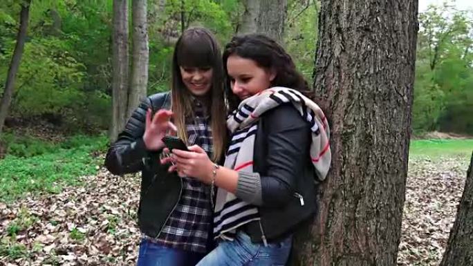 两个快乐的女朋友在公园里用智能手机自拍。索尼uhd steadycam拍摄，股票视频