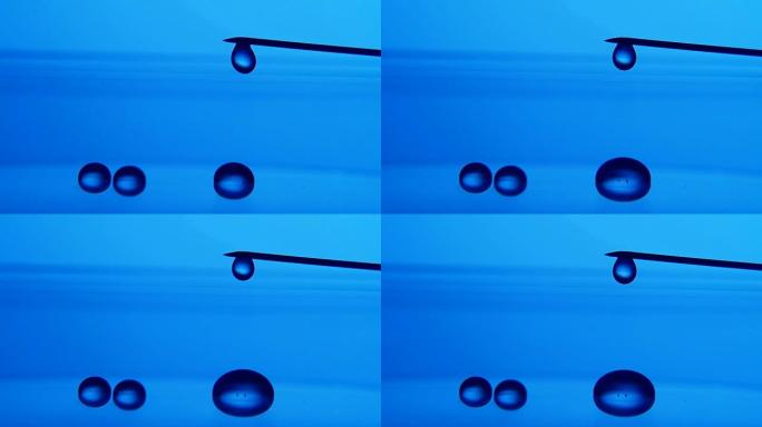 闪亮的水滴从实验室蓝色表面上的金属针上掉下来