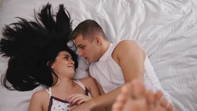 Happy loving couple in bed, smiling and touching e