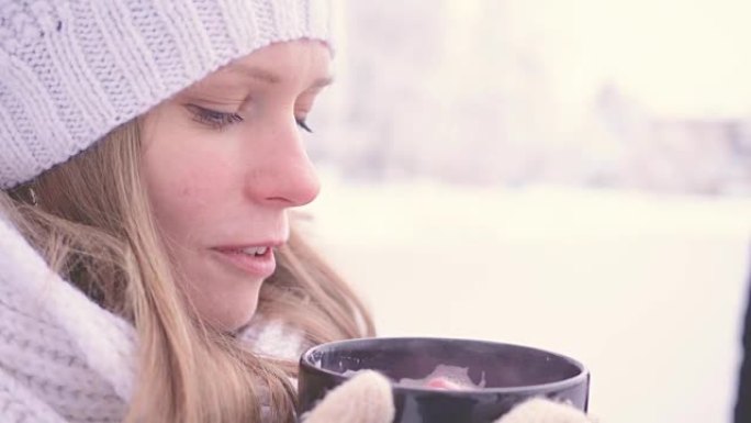 美丽的年轻女孩在公园外面喝热巧克力，闻起来很暖和。舒适的概念。全高清FHD 3840 2160慢动作