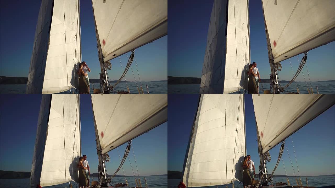 相机正在转移到年轻的情侣在帆船上拥抱。