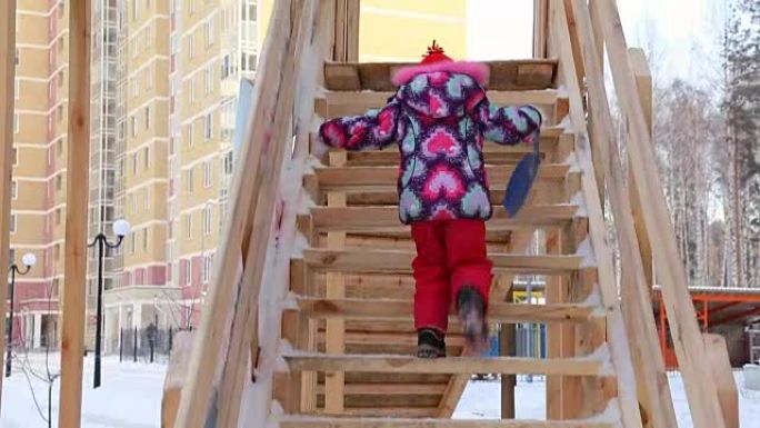 Child is climbing up slide stairs at playground