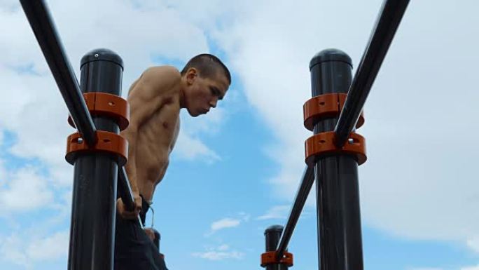 一个瘦弱而肌肉发达的家伙在健身杆上训练。