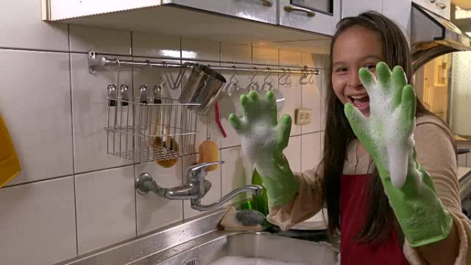 亚裔美国女孩开心地做洗碗工，露出泡沫的手
