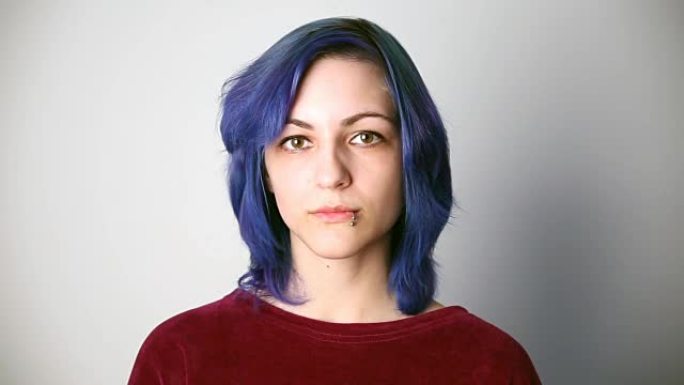 现代青年。一个严肃的女孩的平静肖像，外表异常，有着蓝色的头发和穿孔。
